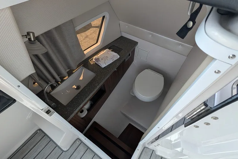 Slide: The Image of 2019 Four Winns H290 OB boat bathroom with sink, toilet, and window. - 24