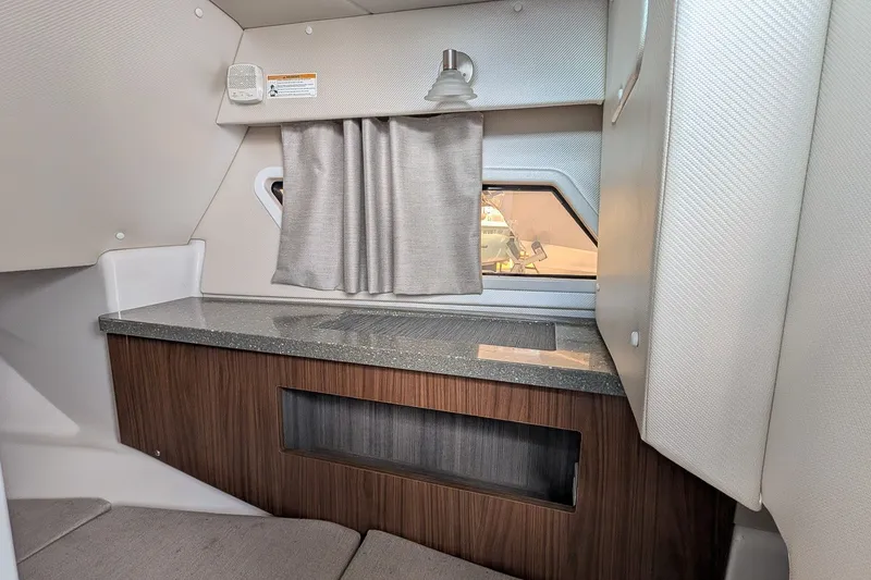 Slide: The Image of 2019 Four Winns H290 OB cabin interior with window, curtain, and wooden cabinetry. - 20