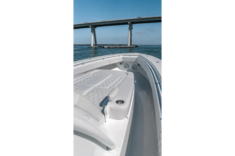 Slide: The Image of 2024 Contender 44 Fisharound boat with sleek seating, cruising under a bridge on open water. - 46