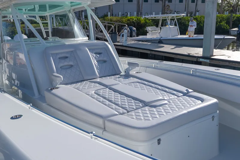 Slide: The Image of 2024 Contender 44 Fisharound boat with luxurious seating and sleek design at a marina. - 2