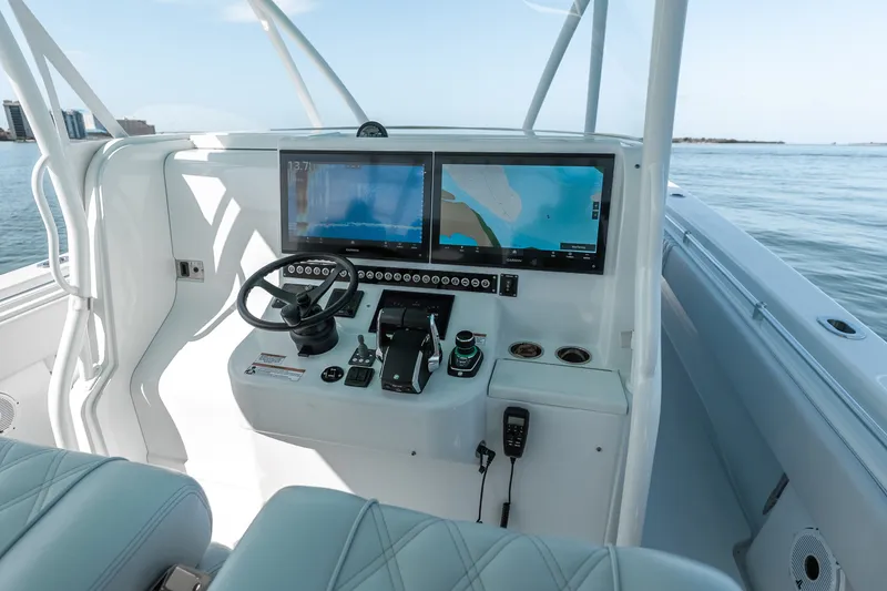 Slide: The Image of 2024 Contender 44 Fisharound helm with dual navigation screens and steering wheel on open water. - 33