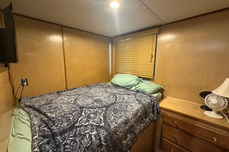 Slide: The Image of Cozy bedroom in 1988 Stardust Cruisers 16x65 houseboat with wooden walls and patterned bedding. - 6