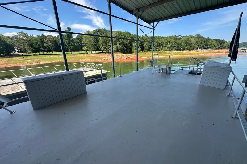 Slide: The Image of Spacious deck of 1988 Stardust Cruisers 16x65 houseboat, overlooking serene lake and lush greenery. - 15