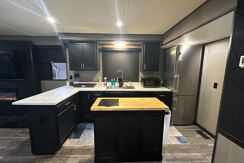 Slide: The Image of Modern kitchen interior in a 1988 Stardust Cruisers 16x65 houseboat, featuring sleek black cabinetry. - 4