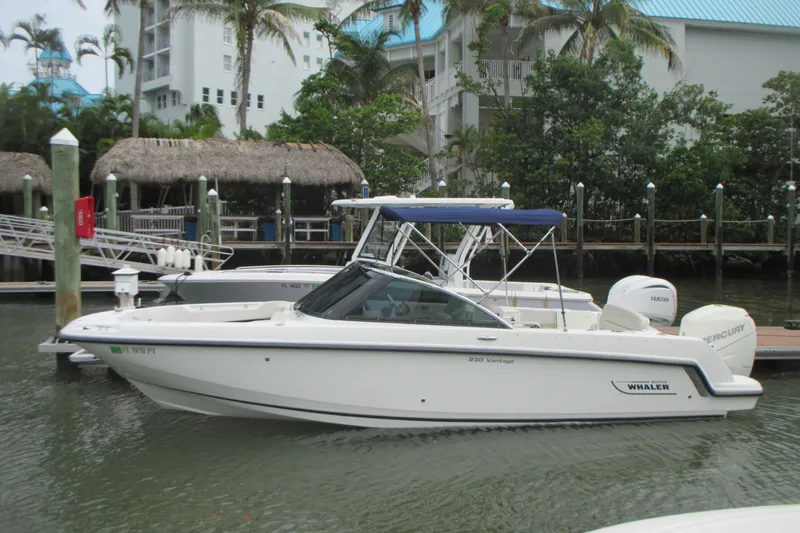 The Image of 2013 Boston Whaler 230 Vantage boat docked in a marina with tropical surroundings. - 0