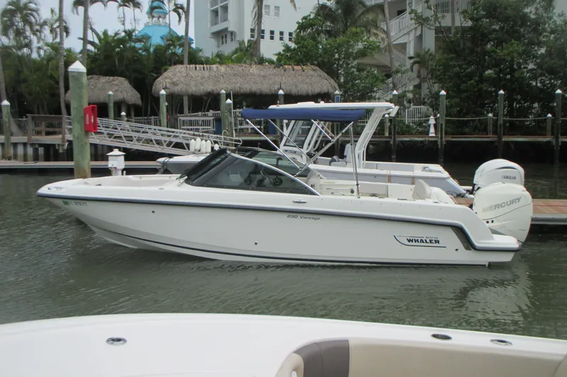 Slide: The Image of 2013 Boston Whaler 230 Vantage boat docked in a marina setting. - 1