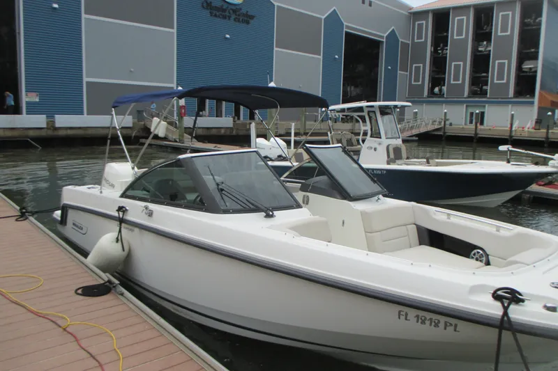Slide: The Image of 2013 Boston Whaler 230 Vantage docked at a marina with blue buildings. - 4