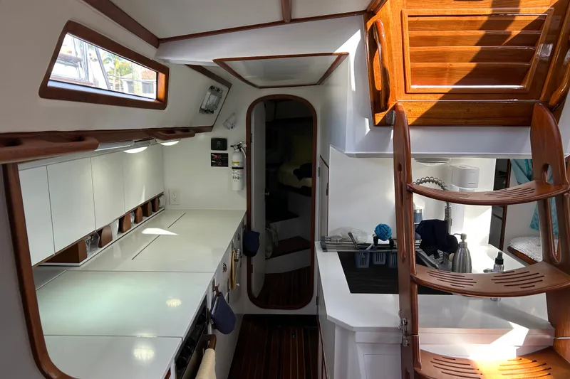 Slide: The Image of Interior of a 1989 Hylas 44 yacht featuring a sleek kitchen and wooden staircase. - 26