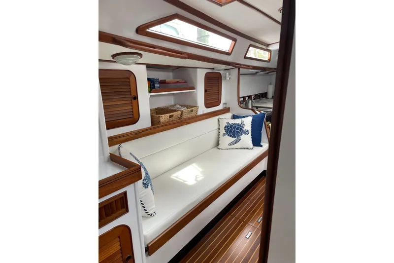 Slide: The Image of Interior of 1989 Hylas 44 yacht with white seating and nautical-themed pillows. - 22