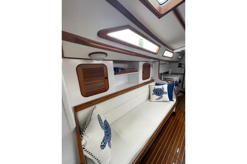 Slide: The Image of Interior of 1989 Hylas 44 yacht with white seating, wooden accents, and nautical-themed pillows. - 23