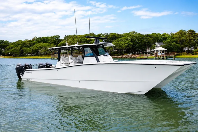 Slide: The Image of 2023 Freeman 43 boat on calm water, surrounded by lush greenery and a clear sky. - 1