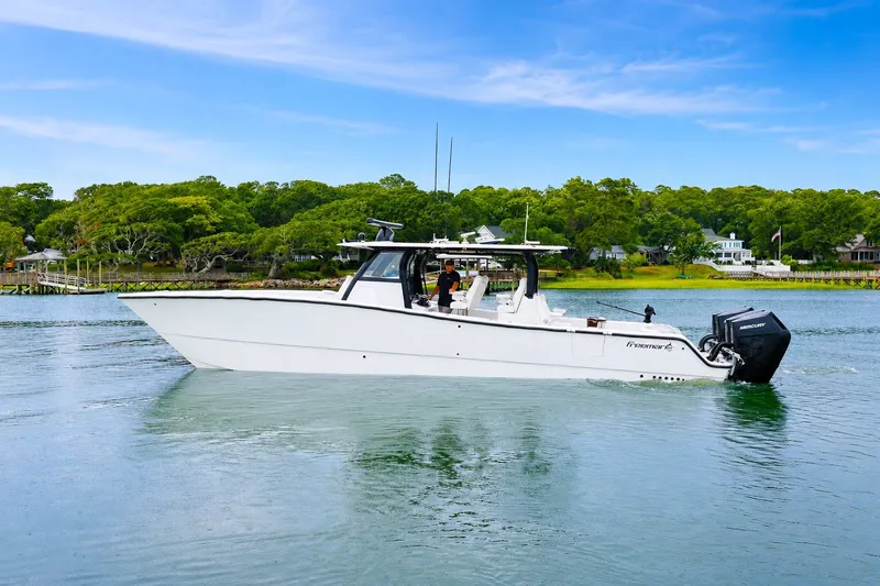 Slide: The Image of 2023 Freeman 43 boat cruising on a serene lake with lush green shoreline. - 2