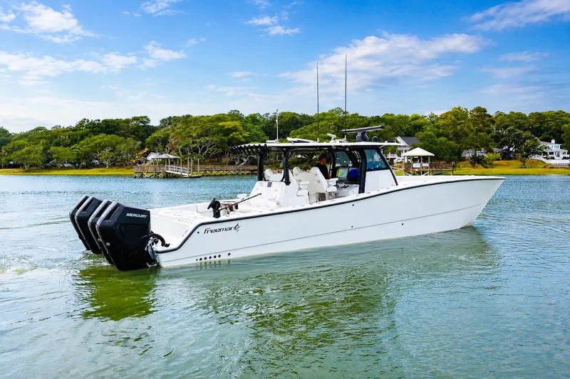 Slide: The Image of 2023 Freeman 43 boat cruising on a serene lake with lush greenery in the background. - 3