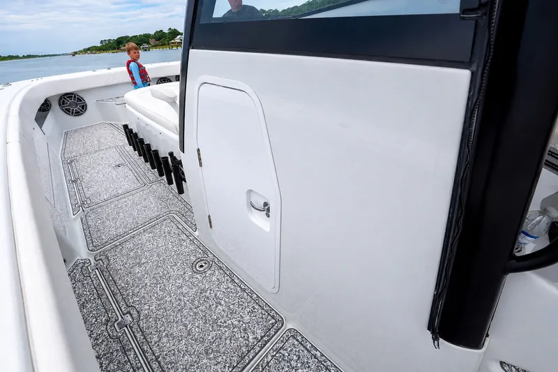 Slide: The Image of 2023 Freeman 43 boat interior with rod holders and seating, cruising on a scenic waterway. - 19