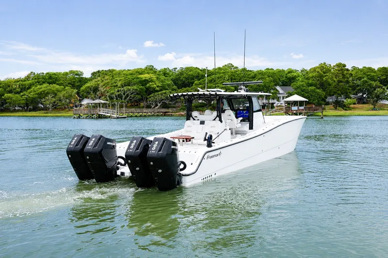 Slide: The Image of 2023 Freeman 43 boat with four engines cruising on a scenic lake. - 4