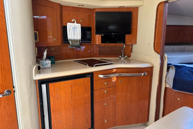 Slide: The Image of 2001 Sea Ray 340 Amberjack interior with kitchenette, TV, and wood cabinetry. - 11
