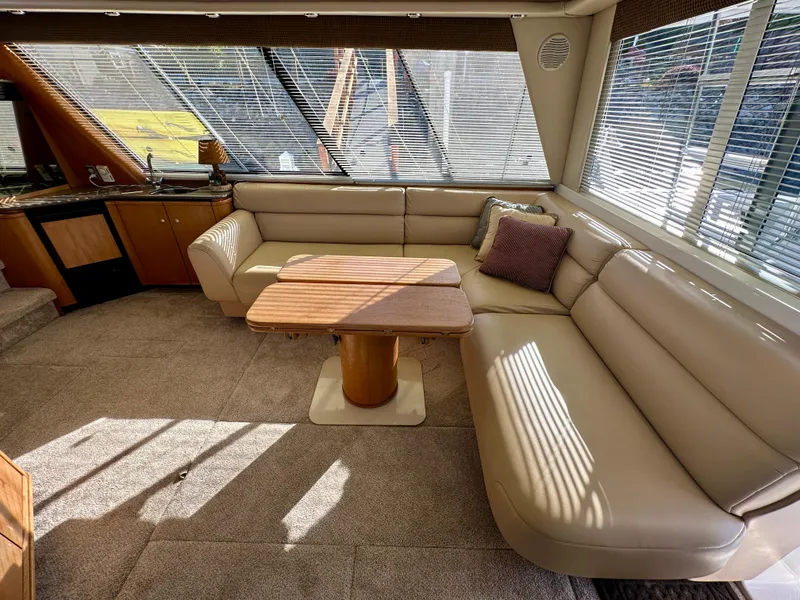 Slide: The Image of Interior of a 1999 Bayliner 4788 with beige sofa and wooden table. - 20