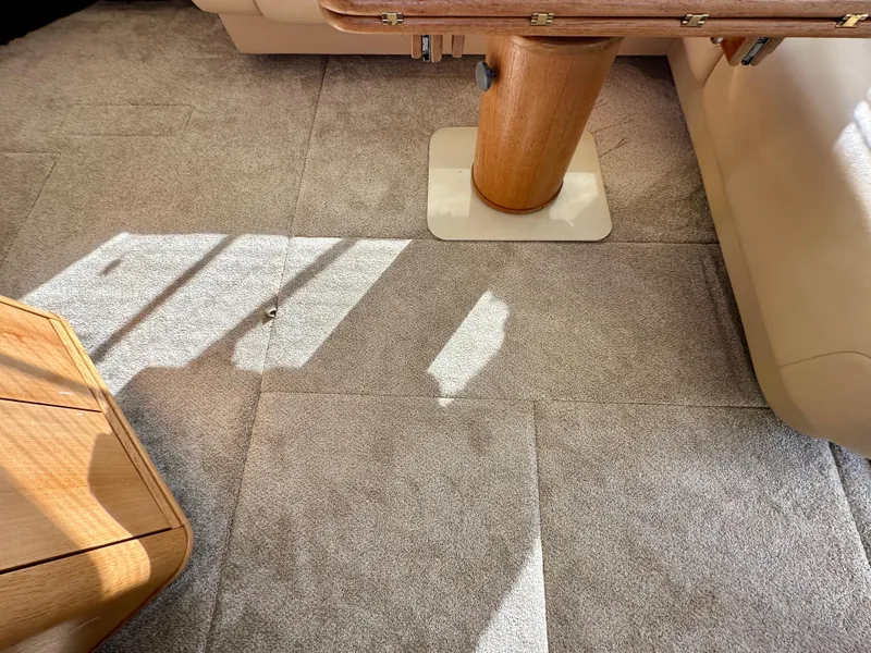 Slide: The Image of Carpeted interior of a yacht with a wooden table and seating area. - 24