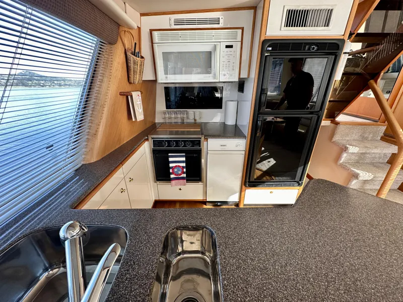 Slide: The Image of The 1999 Bayliner 4788 Pilot House Motoryacht's kitchen features modern appliances, including a microwave, stove, and refrigerator. - 31
