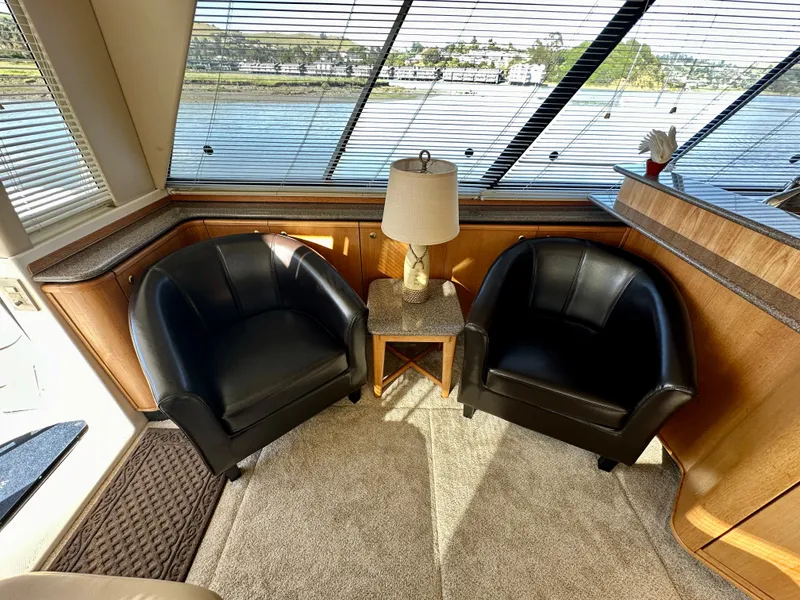 Slide: The Image of Interior of the 1999 Bayliner 4788 with two black chairs and a table by a window. - 18