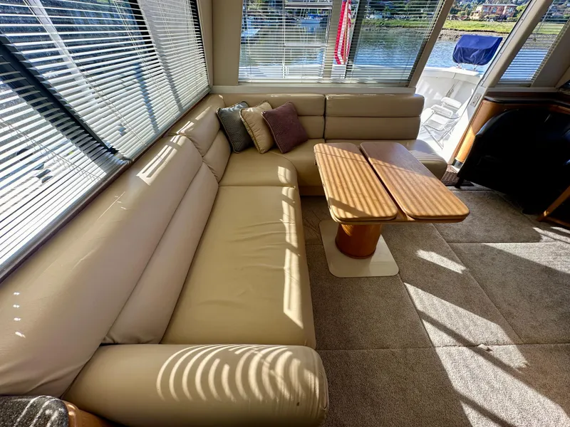 Slide: The Image of The image shows the interior of a 1999 Bayliner 4788 Pilot House Motoryacht with a beige leather sofa and wooden table. - 21