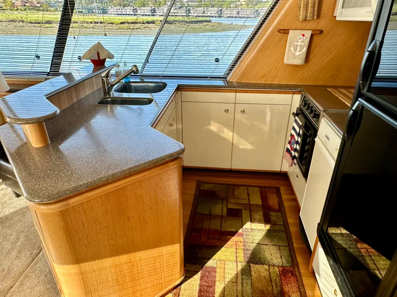 Slide: The Image of The 1999 Bayliner 4788 kitchen features a countertop, sink, and appliances with a water view. - 29