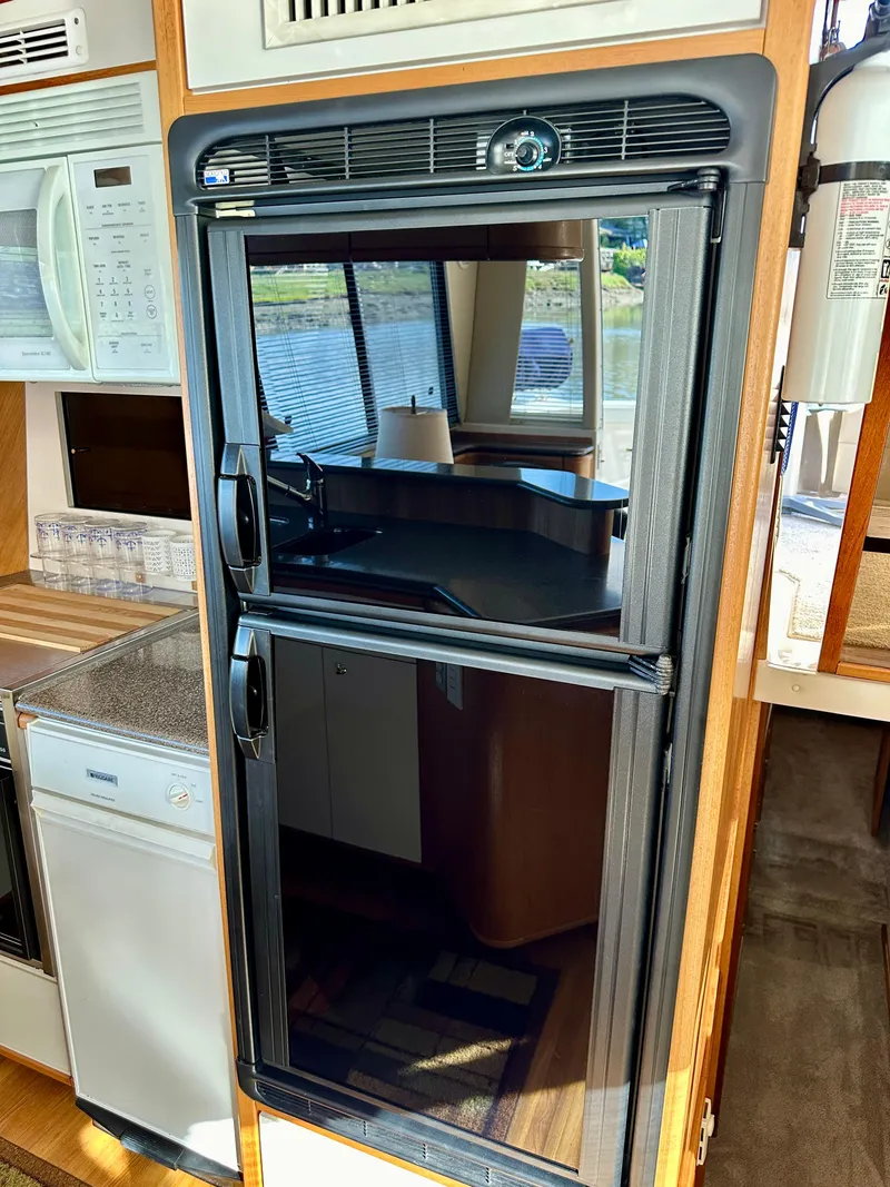 Slide: The Image of The 1999 Bayliner 4788 Pilot House Motoryacht's kitchen features a refrigerator and a sink. - 32