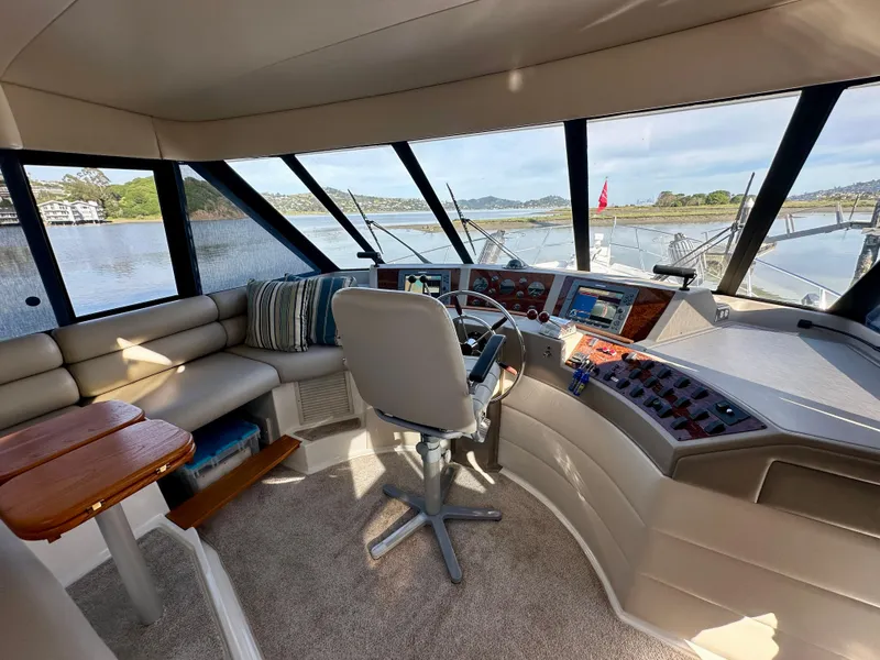 Slide: The Image of The image shows the helm of a 1999 Bayliner 4788 Pilot House Motoryacht with panoramic windows and a comfortable seating area. - 14