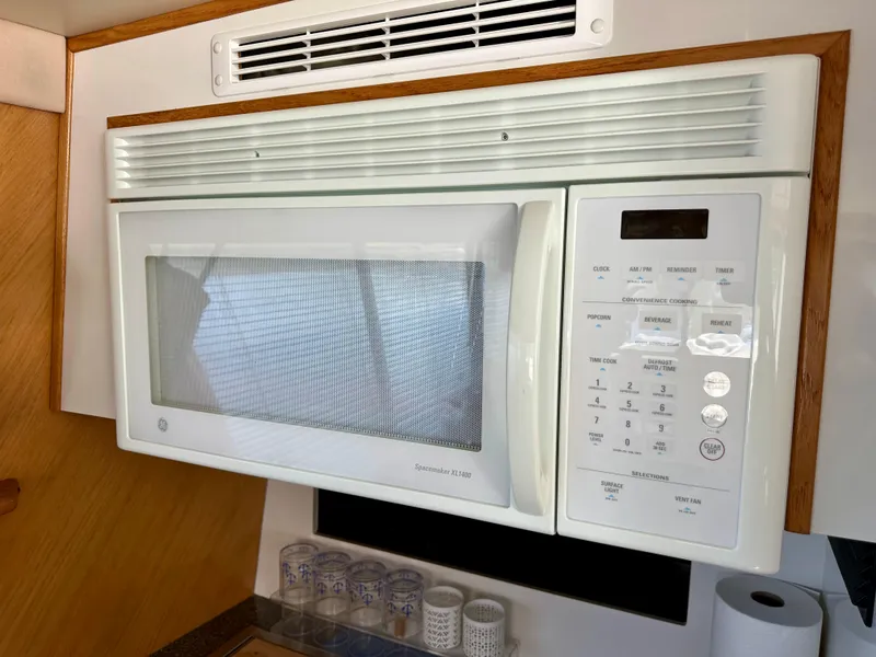 Slide: The Image of A microwave in a boat's galley with wood paneling and glasses below. - 34