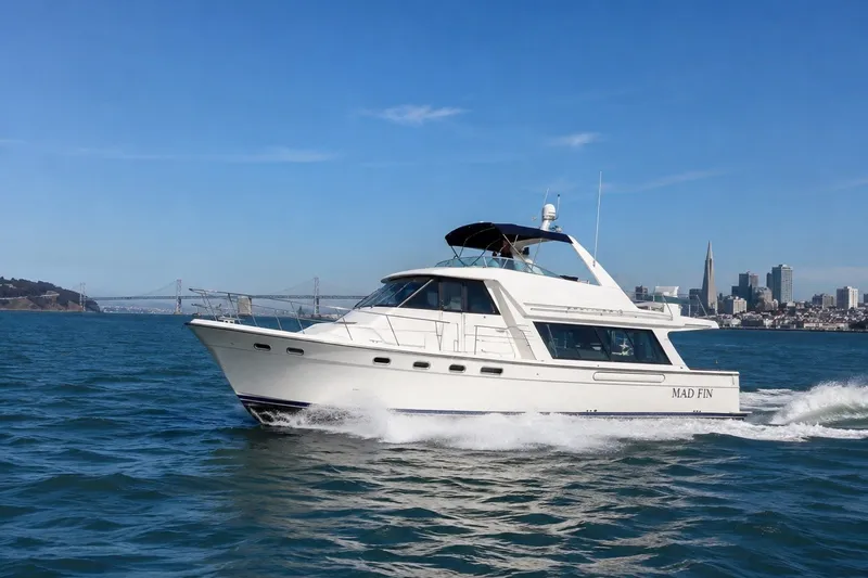 The Image of 1999 Bayliner 4788 Pilot House Motoryacht cruising near city skyline and bridge. - 0