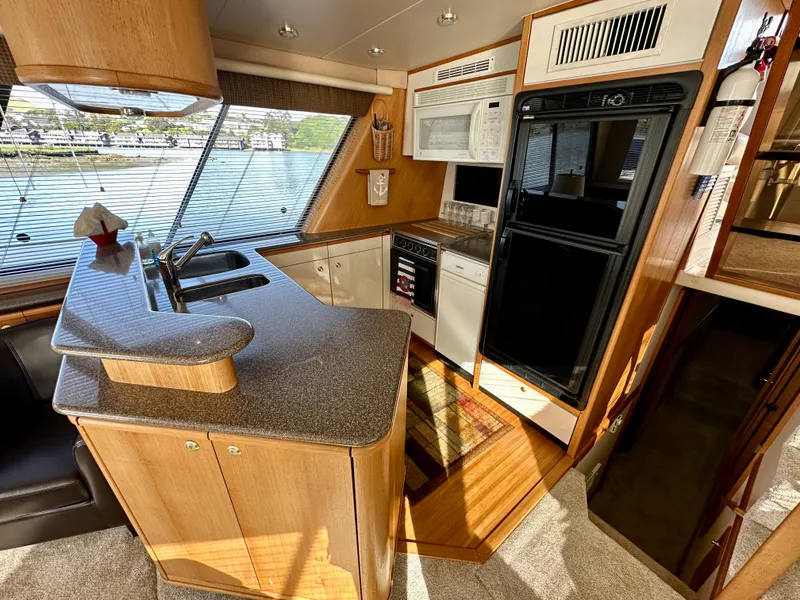 Slide: The Image of The 1999 Bayliner 4788 Pilot House Motoryacht's kitchen features modern amenities, including a sink, stove, and microwave. - 30