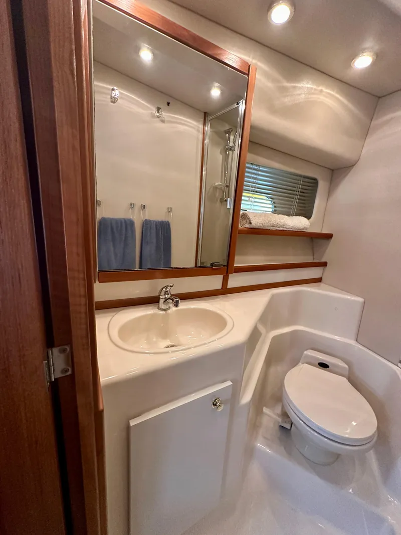 Slide: The Image of The image shows a bathroom in a 1999 Bayliner 4788 Pilot House Motoryacht. It features a sink, toilet, and mirror. - 46