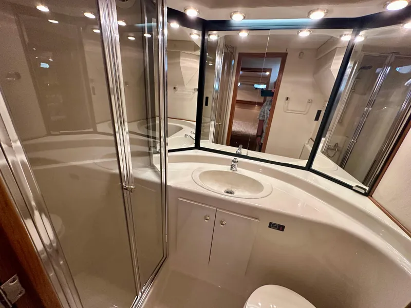 Slide: The Image of The image shows a sleek bathroom with a shower, sink, and mirror in a 1999 Bayliner 4788 Pilot House Motoryacht. - 49