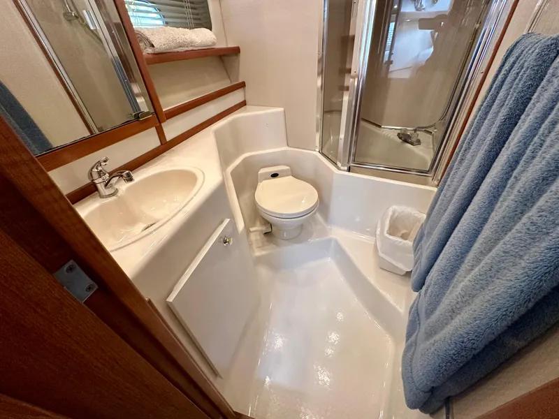 Slide: The Image of The image shows a yacht bathroom with a sink, toilet, and shower. Towels hang on the wall. - 45