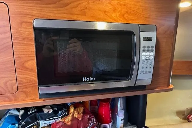 Slide: The Image of Haier microwave in 2014 Rinker 260 Express Cruiser kitchen with wooden cabinetry. - 19