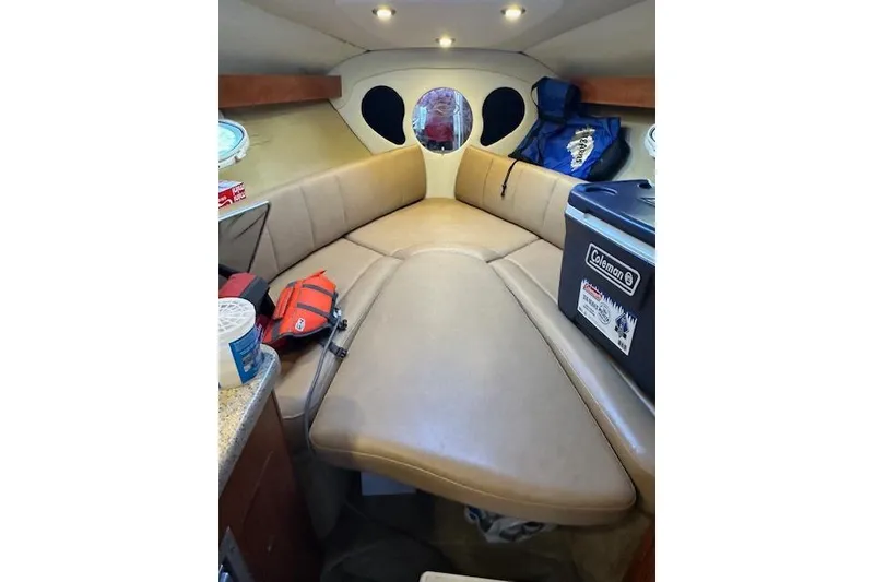 Slide: The Image of 2014 Rinker 260 Express Cruiser cabin interior with beige seating and storage items. - 18