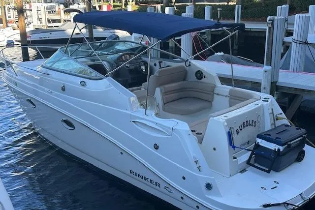 The Image of 2014 Rinker 260 Express Cruiser docked with blue canopy and seating area. - 0