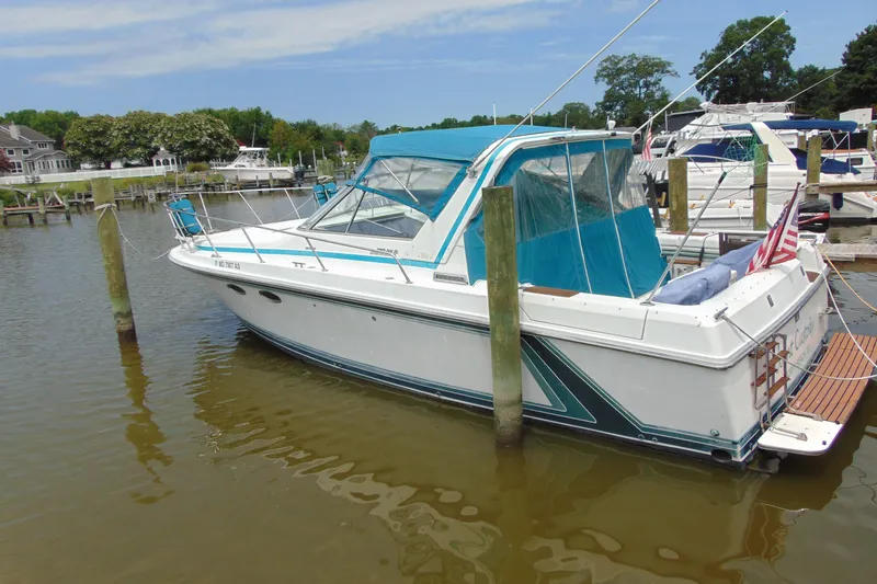 The Image of 1988 TROJAN INTERNATIONAL 10M boat docked in a marina with blue canopy. - 3