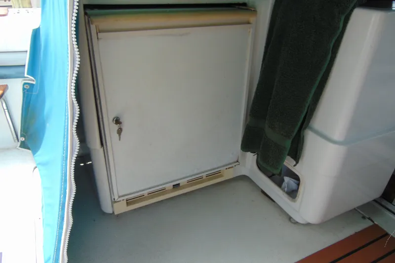 Slide: The Image of 1988 Trojan International 10M boat interior with a closed storage compartment and blue fabric cover. - 16