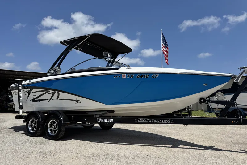The Image of 2014 Tigé Z1 boat on trailer, blue and white design, parked outdoors. - 1