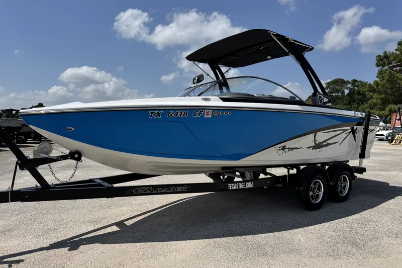 Slide: The Image of 2014 Tigé Z1 boat in blue and white on a trailer under a sunny sky. - 8