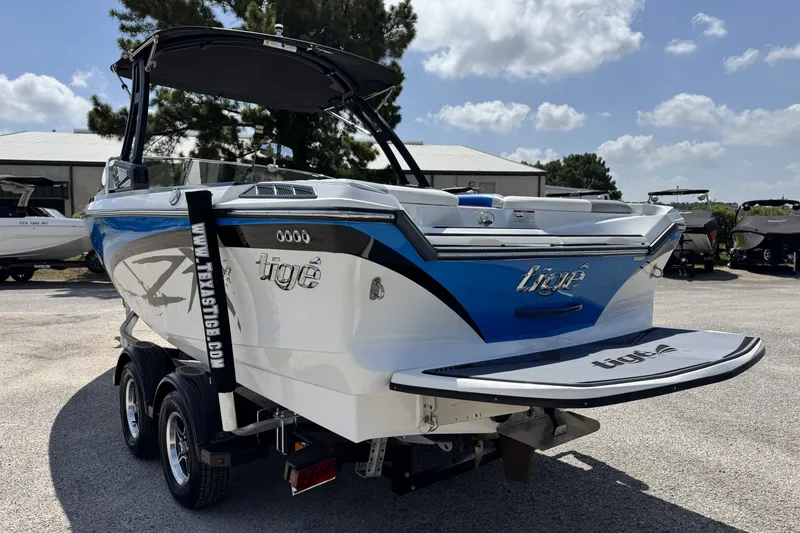 Slide: The Image of 2014 Tigé Z1 boat with blue and white design, parked on a trailer under a sunny sky. - 6