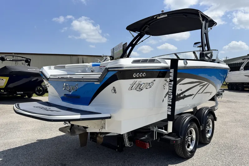 Slide: The Image of 2014 Tigé Z1 boat on trailer, blue and white design, sunny day background. - 4