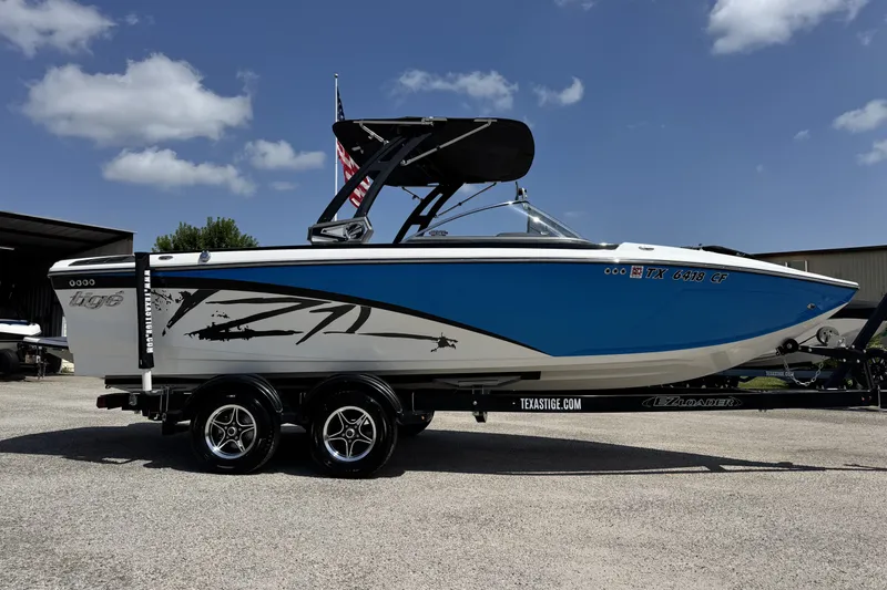 Slide: The Image of 2014 Tigé Z1 boat with blue and white design on a trailer, under a clear sky. - 3