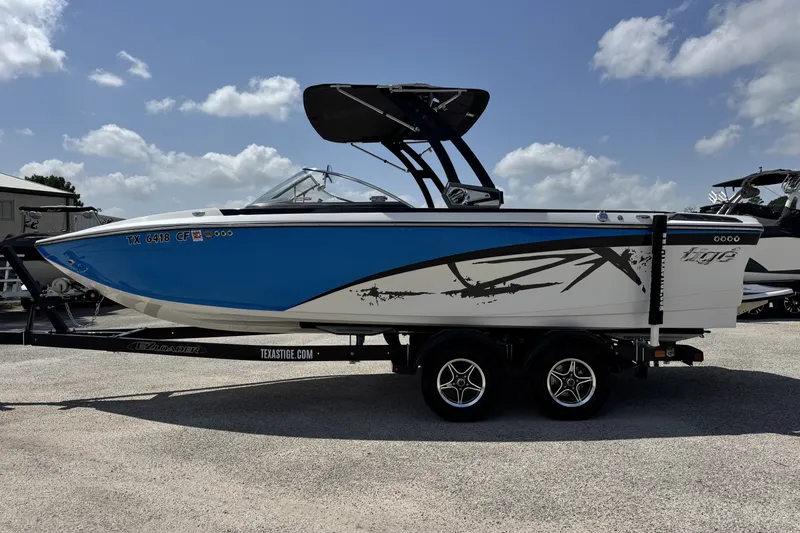 Slide: The Image of 2014 Tigé Z1 boat with blue and white design on a trailer under a clear sky. - 7