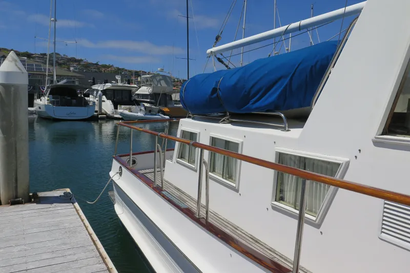 Slide: The Image of 1988 Grand Banks 36 Classic yacht docked at a marina, featuring wooden railings and blue cover. - 5