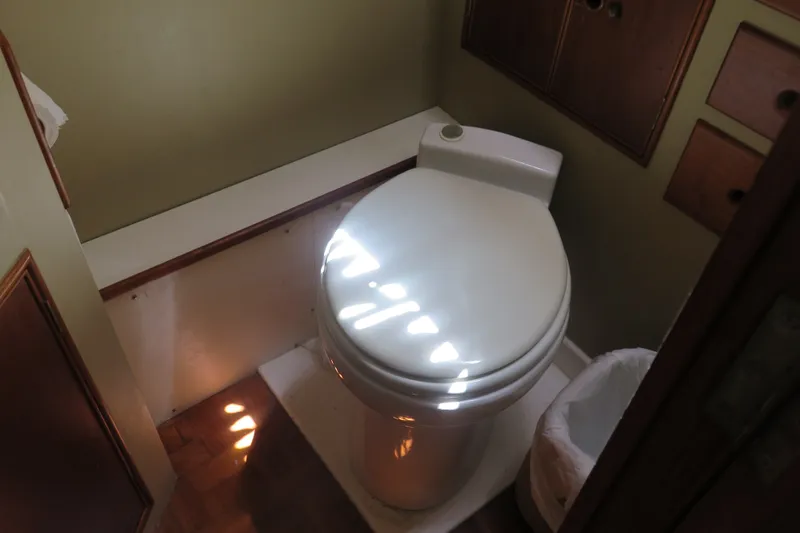 Slide: The Image of 1988 Grand Banks 36 Classic boat bathroom with toilet and wooden cabinetry. - 31