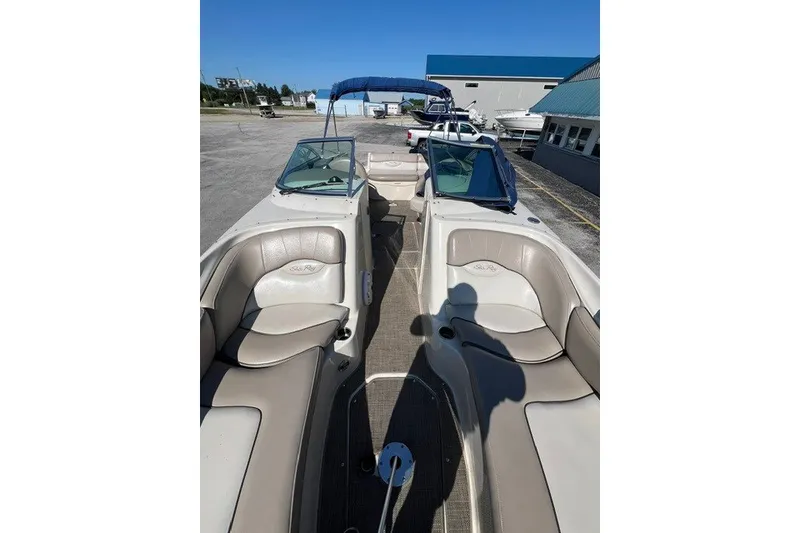 Slide: The Image of 2003 Sea Ray 240 Sundeck boat with beige seating and blue canopy, parked outdoors. - 3