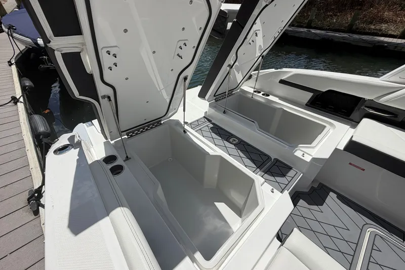 Slide: The Image of Open storage compartments on a 2027 Cobalt R6 Outboard boat docked by the water. - 9