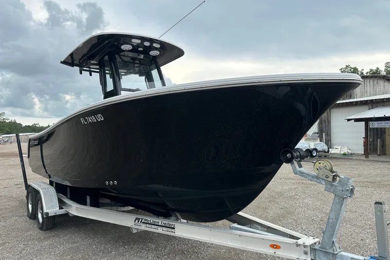 The Image of 2026 Sportsman Open 232 Center Console boat on trailer, parked outdoors under cloudy sky. - 0